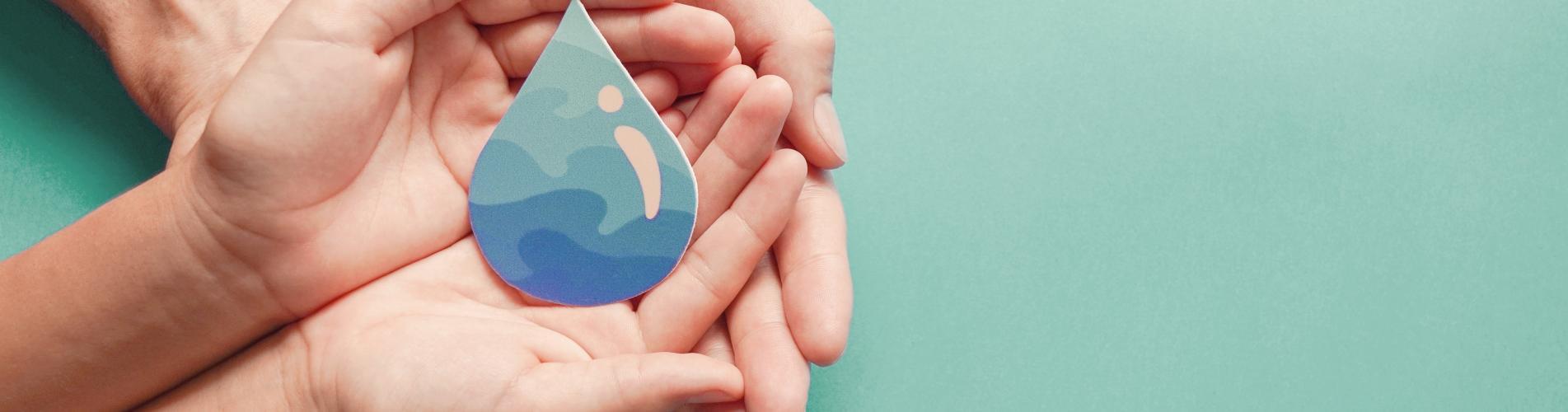 Photo d'une goutte d'eau posée sur deux paires de mains superposées