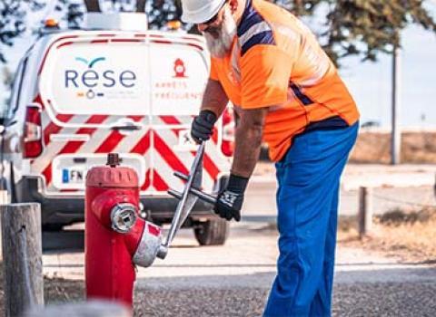 Un salarié de la RESE effectue un contrôle de routine sur un poteau de défense extérieure contre l'incendie.