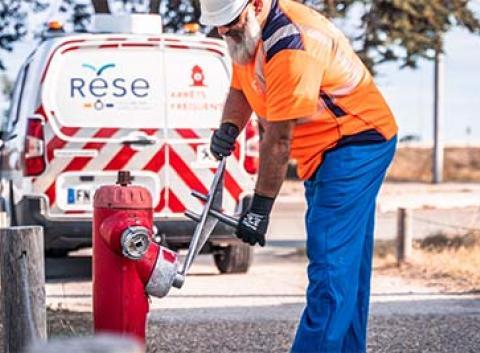 Un salarié de la RESE effectue un contrôle de routine sur un poteau de défense extérieure contre l'incendie.